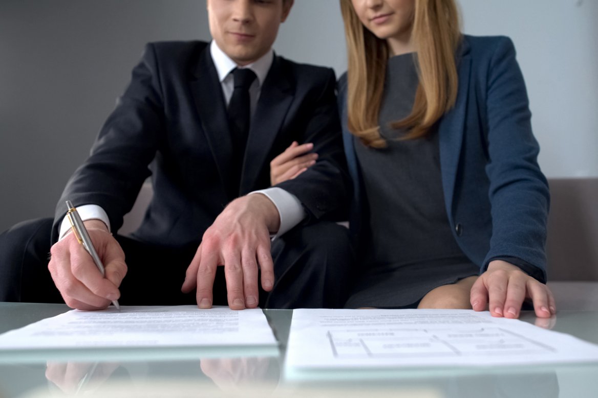 young couple signing will and other estate planning documents