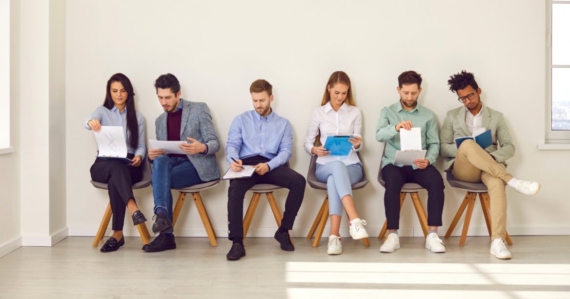 six people in chairs waiting to be interviewed for a job