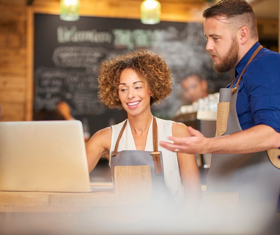 cafe owners discuss information they see on laptop